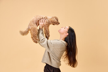 One beautiful young girl lovely looking at her cute pet with love and playing with her against...