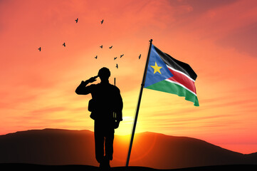 Silhouette of a soldier with the South Sudan flag stands against the background of a sunset or...