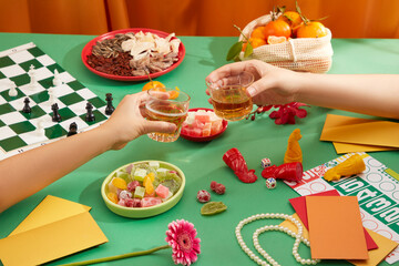 The two of them were clinking two beer glasses, a seahorse and chess set was displayed on the table with a variety of jams, dried nuts, a basket of tangerines and lucky money envelopes. Copy space. © Tuan  Nguyen 