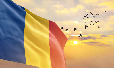 Waving flag of Romania against the background of a sunset or sunrise. Romania flag for Independence...