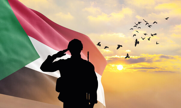 Silhouette of a soldier with the Sudan flag stands against the background of a sunset or sunrise. Concept of national holidays. Commemoration Day.