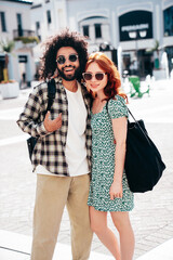 Smiling beautiful redhead  woman and her handsome boyfriend. Model in casual summer clothes. Happy cheerful family. Female having fun. Couple posing in the street at sunny day