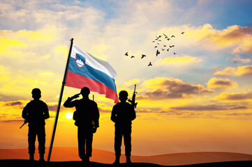 Silhouettes of soldiers with the Slovenia flag stand against the background of a sunset or sunrise. Concept of national holidays. Commemoration Day.
