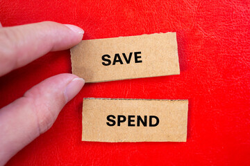 Save or spend lettering on ripped cardboard paper with red background. Conceptual photo. Top view, copy space.