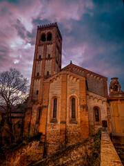 old historical Italian medieval stone church illuminated in autumn against clouded dark evening sky