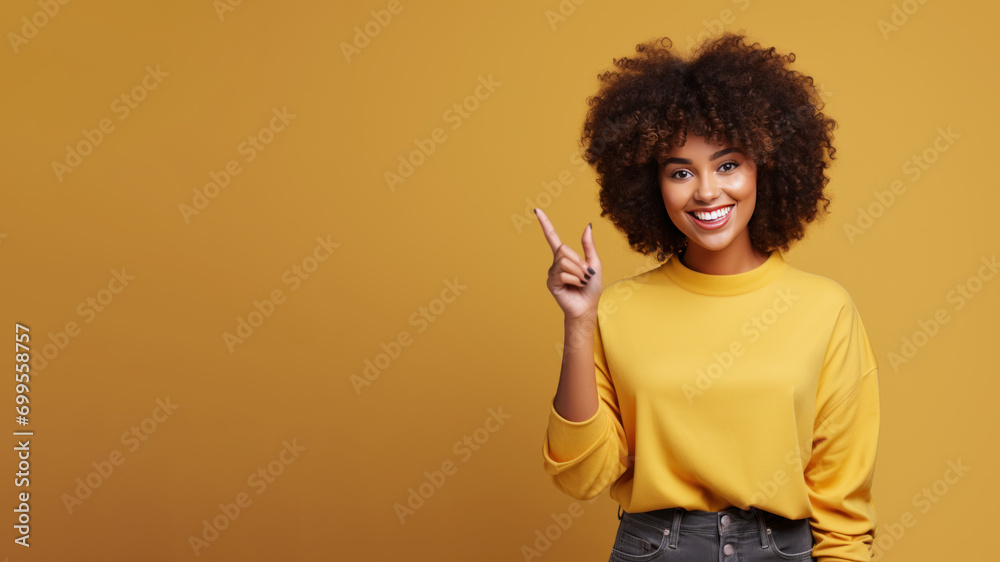 Wall mural Happy afro woman pointing her finger at copy space for promotion