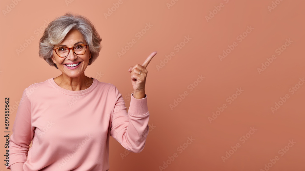 Wall mural Happy senior brunette woman point her finger at copy space for promotion