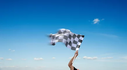 Foto op Canvas Checkered race flag in hand against blue sky © xy