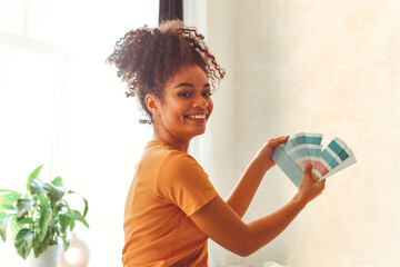 Smiling African American girl stands back to camera in middle of bed room with palette of blue...