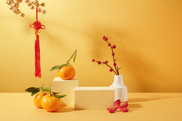 Tangerines, two wooden platforms, a flower vase and Tet decorations are displayed on a yellow...