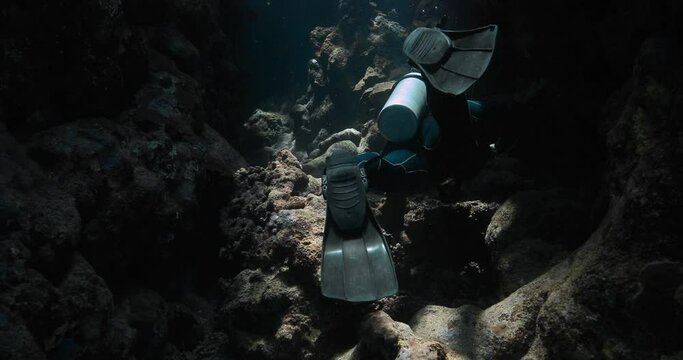 a dark underwater cave getting explored by a scuba diver