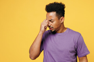 Young sad sick ill tired man of African American ethnicity he wears purple t-shirt casual clothes...