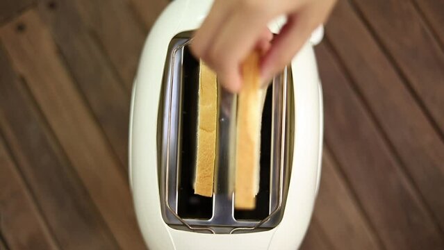 Close-up of a slice of white bread popping out of the toaster, preparing breakfast.


