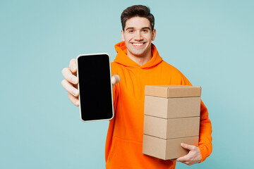 Young man wearing orange hoody casual clothes hold stack cardboard boxes use blank screen mobile...