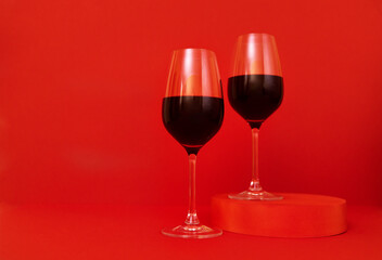 Two glasses of wine on the podium. Red bright background. Minimalism.