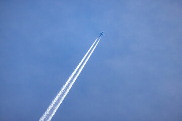 Jet plane with long white trail in blue sky