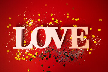 Close up of the word Love on a red background. Bright backdrop with silver sequins and golden round...