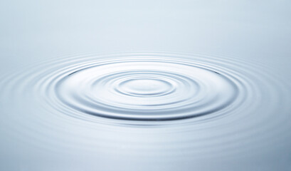 Blue water circles surface with rings and ripples from drop