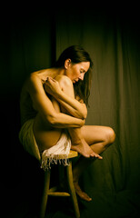 half-naked woman in a romantic pose on a wooden stool