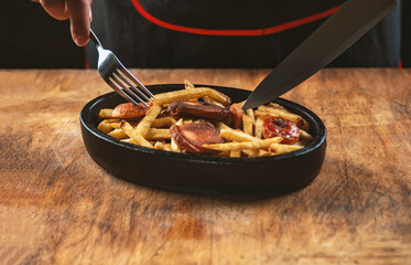 Fried sausages and potatoes in an iron pan