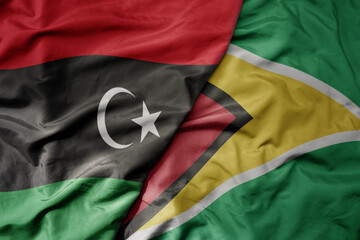big waving national colorful flag of guyana and national flag of libya .