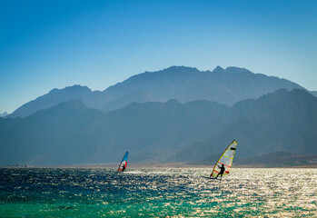 surfers ride in the sea on the background of the rocky coast in Egypt Dahab