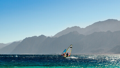 two windsurfers ride on the background of high rocky mountains in Egypt Dahab South Sinai