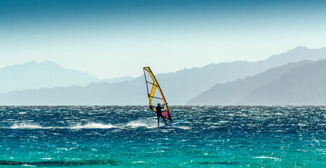 windsurfer rides on a background of high mountains in Egypt Dahab South Sinai - obrazy, fototapety, plakaty