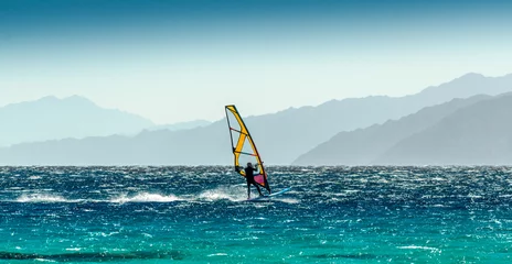 Fotobehang windsurfer rides on a background of high mountains in Egypt Dahab South Sinai © Sofiia