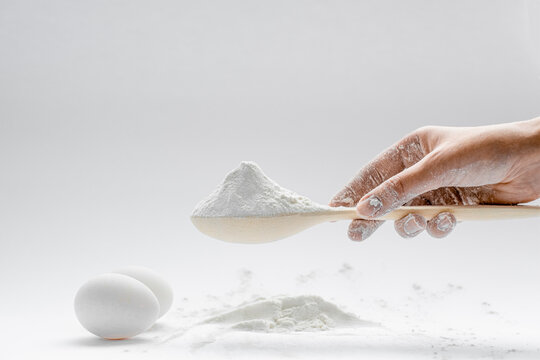 woman scooping white flour with a wooden spoon close-up