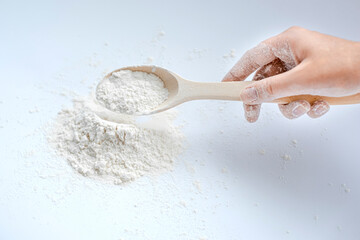 woman scooping white flour with a wooden spoon close-up