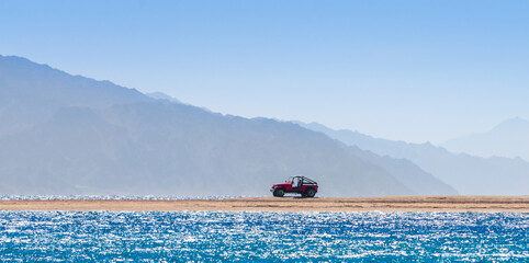 offroad car on an island in the Red Sea against the backdrop of high cliffs in Egypt