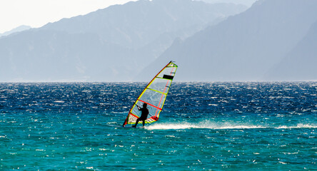 windsurfer on the background of high mountains rides on the waves of the Red Sea in Egypt Dahab...