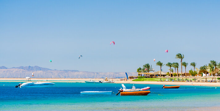 hotel with palm trees on the Red Sea in Egypt Dahab with boats and kite surfers
