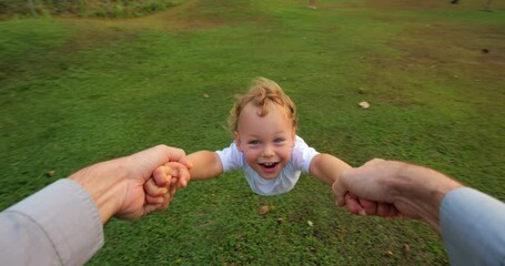 In heartwarming scene shot in slow motion from first-person view, father spins his elated toddler, sharing moment filled with genuine joy and laughter outdoors. This touching display of fatherly love