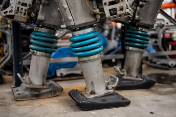 Blue construction rammer parts close up in old oily conditions in warehouse garage workshop for repairing