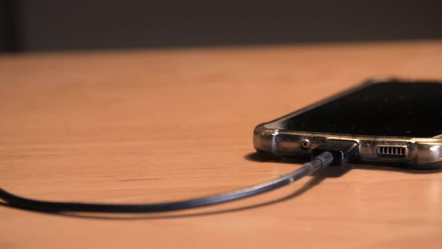 Phone charging on table, slider shot. 
