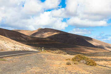 Spectacular view of the volcanic landscape in Timanfaya National Parkwith empty country road. Lanzarote, Canary Islands, Spain, Atlantic, Europe. Tourism and vacations concept.