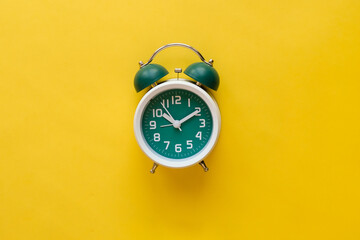 Classic green alarm clock on yellow background