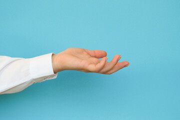 A hand in a white shirt holds something on a blue background