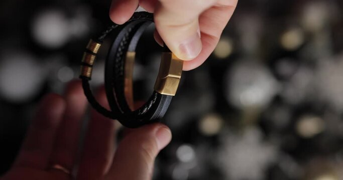 Demonstrating a male black leather bracelet in a hands, vertical video