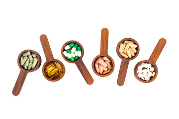 Vitamins and supplements. A variety of vitamin tablets in wooden spoons isolated on a white background. Multivitamin complex for every day. Nutritional supplements.Copy space.Vitamins for immunity