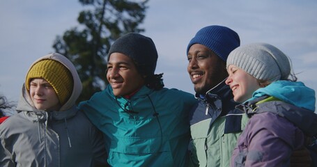 Happy multiethnic friends or family take picture standing on hill against nature scenery. Tourist group of diverse travelers or hiking buddies on trip in mountains. Tourism and active leisure concept.