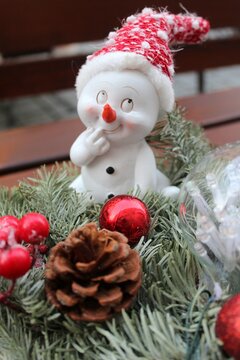Adventskranz mit Weihnachtswichtel, rote Mütze, Christbaumkugeln und Tannenzapfen. Außengastronomie im Dezember. Felle im Hintergrund.