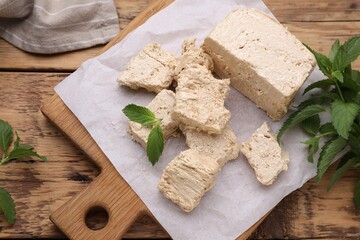 Pieces of tasty halva and mint leaves on wooden table, above view