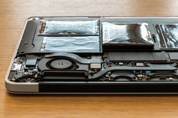 Swollen battery of broken laptop in open casing closeup. Heavy damage of notebook computer...
