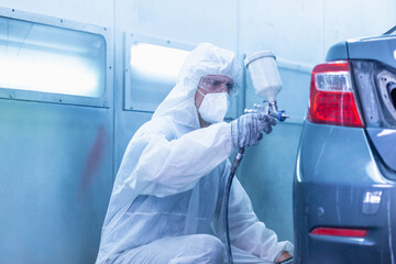 Mechanic painting car in the chamber. Worker using spray gun and airbrush and painting a car,...