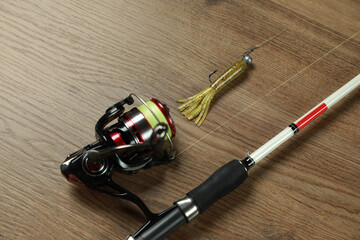 Fishing rod with spinning reel and bait on wooden background, above view