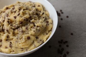 Chocolate chip cookie dough in bowl on gray table, closeup