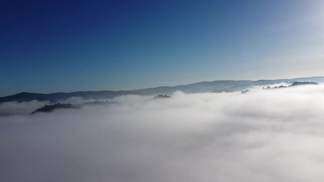 vista de drone sobre nubes a la altura de las monta&ntilde;as en dia soleado.